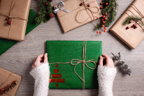 Hands of girl unwrapping a green Christmas gift