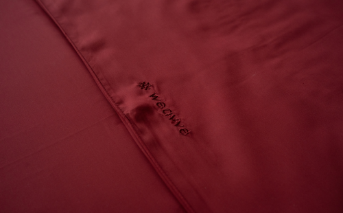 A close-up of a red sheet embroidered with the word Weavve