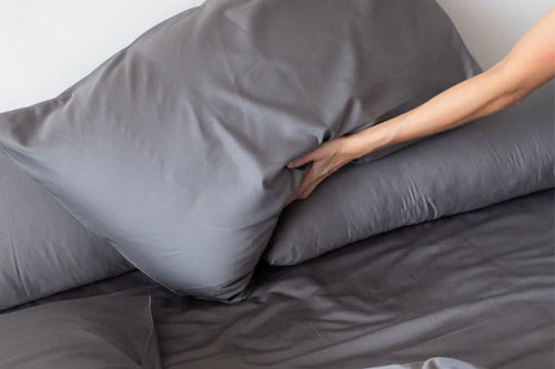 woman arranging bed with cotton fitted and flat sheets