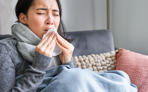 Image of sick korean woman at home covered in warm clothes