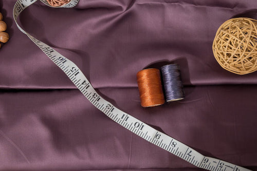 Threads and tape measure used to measure bed sheet size on a dark fabric