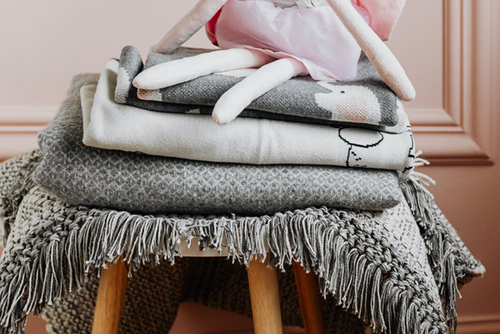Different types of blankets folded on top of a wooden chair
