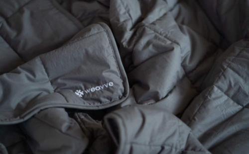 A close up of a grey weighted blanket with the Weavve logo
