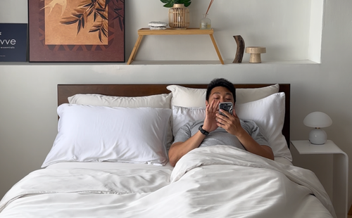 A man watching his phone on bed