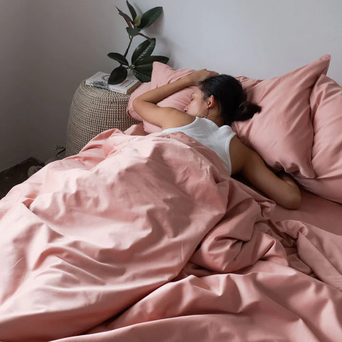 Girl lying on bed with Weavve’s cotton classic set in tea rose