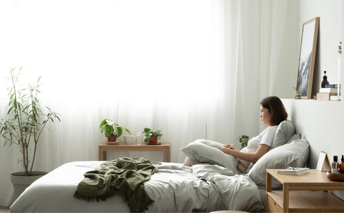 Woman in bed with laptop featuring Signature TENCEL™ in mist grey 