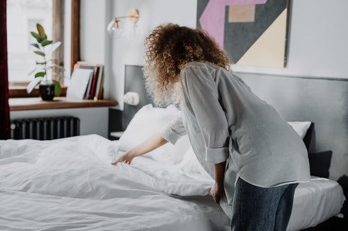 Woman putting on a duvet cover on her bed 