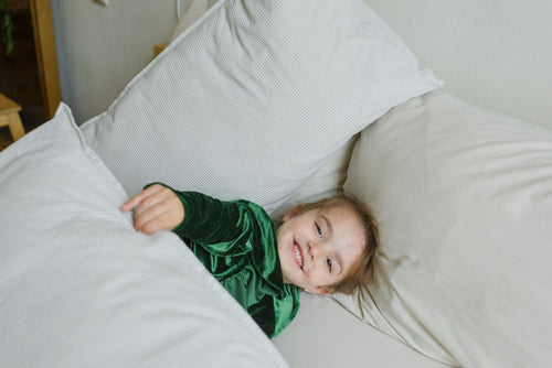 Child lying on bed with pillows and weighted blankets pros and cons