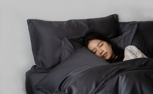 girl sleeping on slate grey bed sheets