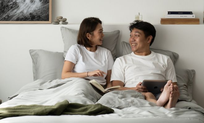couple sitting on bed with grey cooling bedsheets
