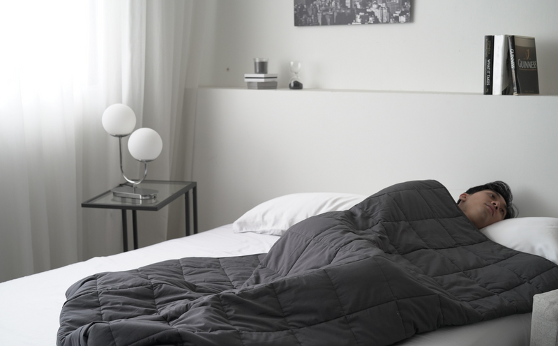 man with anxiety before bed staring at the wall bundled up in a weighted blanket