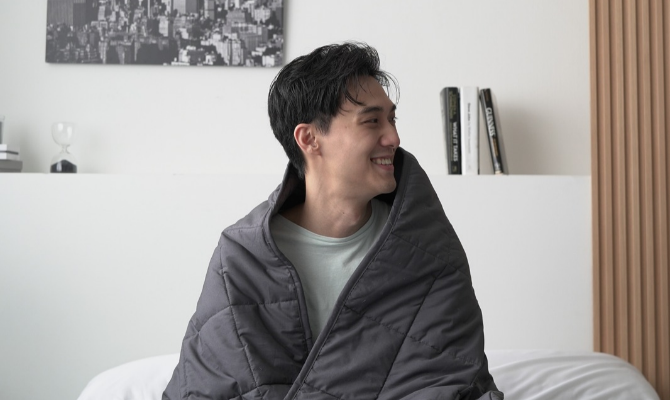 man wrapped in weighted blanket smiling as he looks sideways