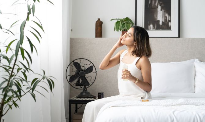 woman doing skincare while sitting on white bed