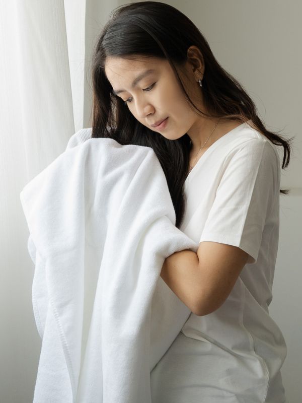 woman drying her hair with white silver infused cotton towel