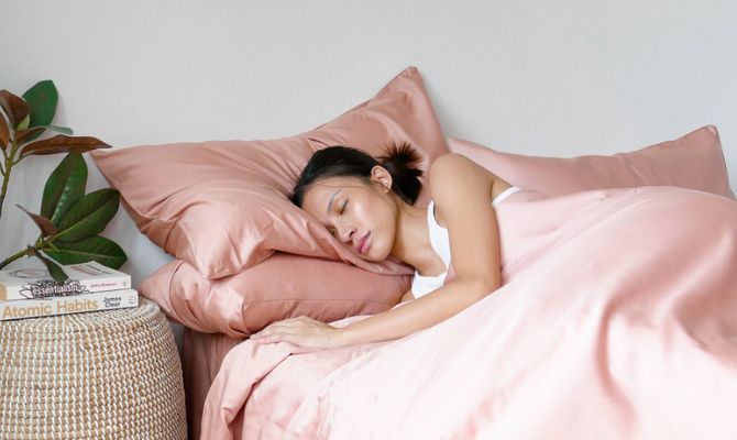 woman sleeping on pink cotton sheets