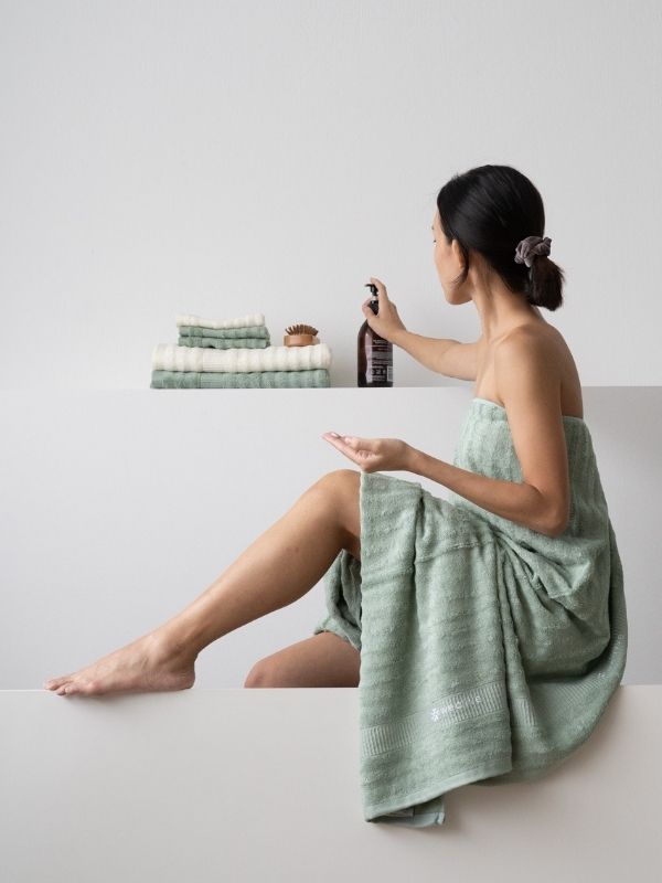 woman wrapped in bamboo towel getting lotion